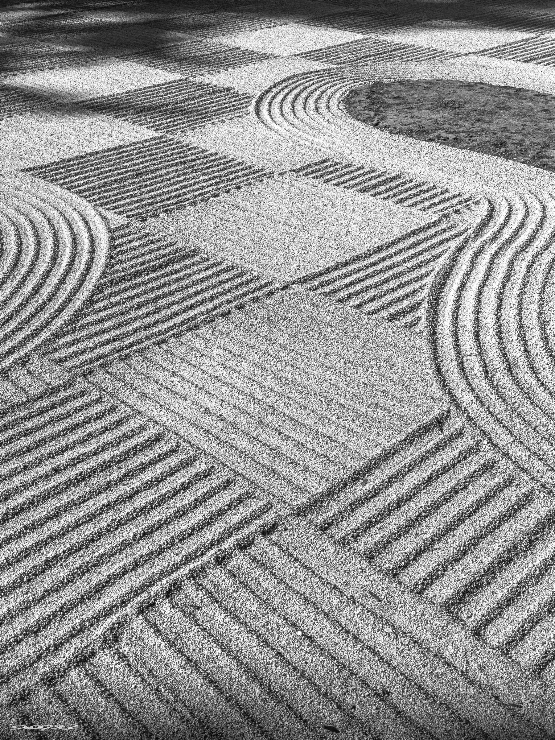 A  Ichimatsu Mori raked Japanese garden features intricate patterns in the gravel with a patch of green moss or grass. Ichimatsu - the checker board pattern is used once a year to celebrate the harvest moon. (mono chrome version.)