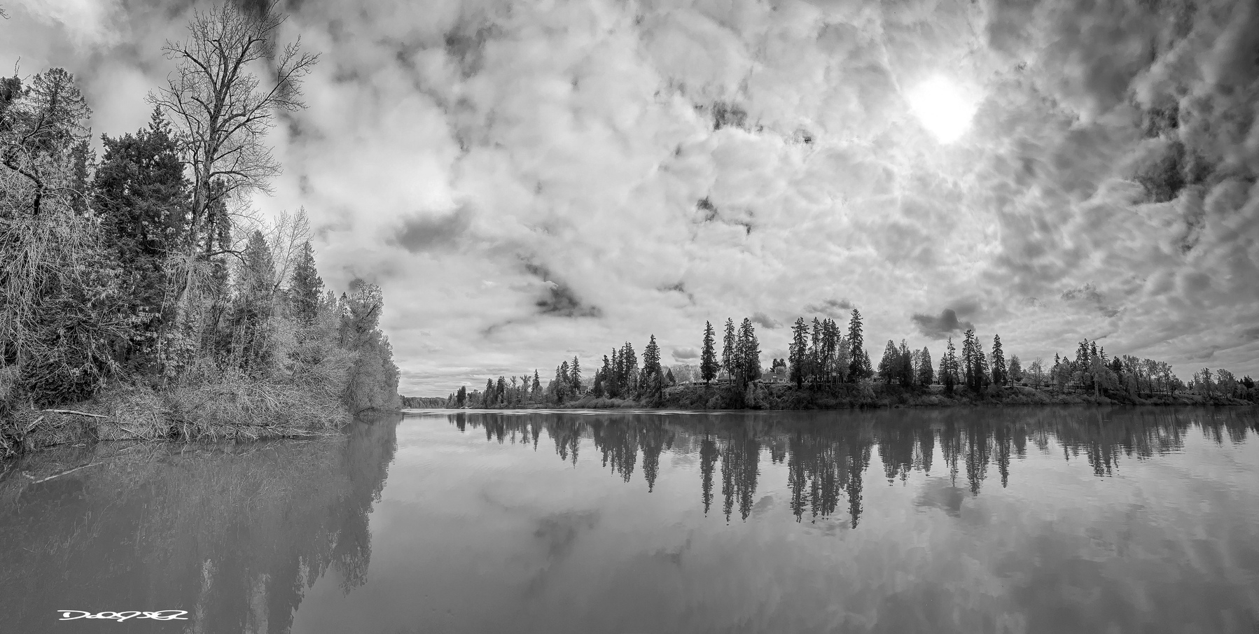 A calm Willamette River and a spring sky covered in mixed clouds