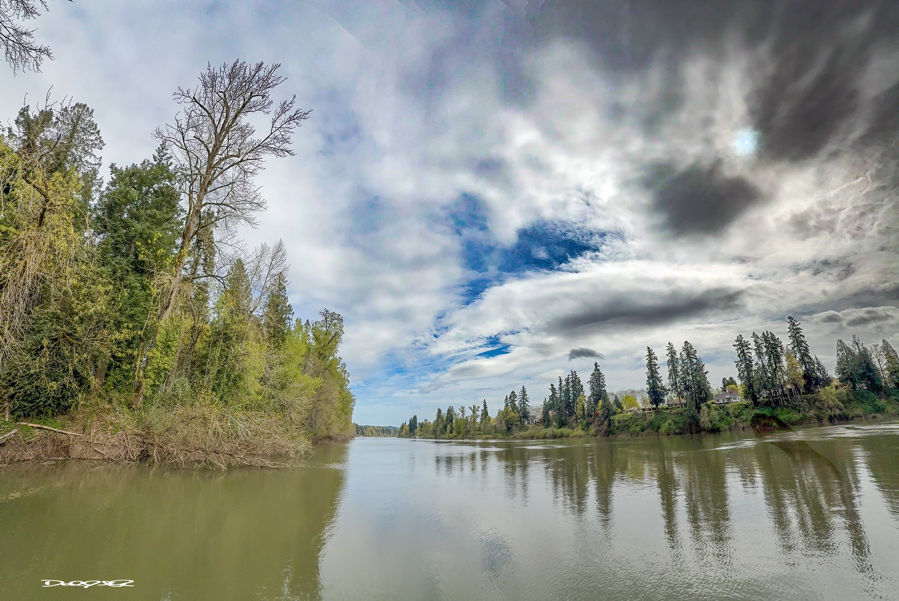 A calm Willamette River and a spring sky covered in mixed clouds