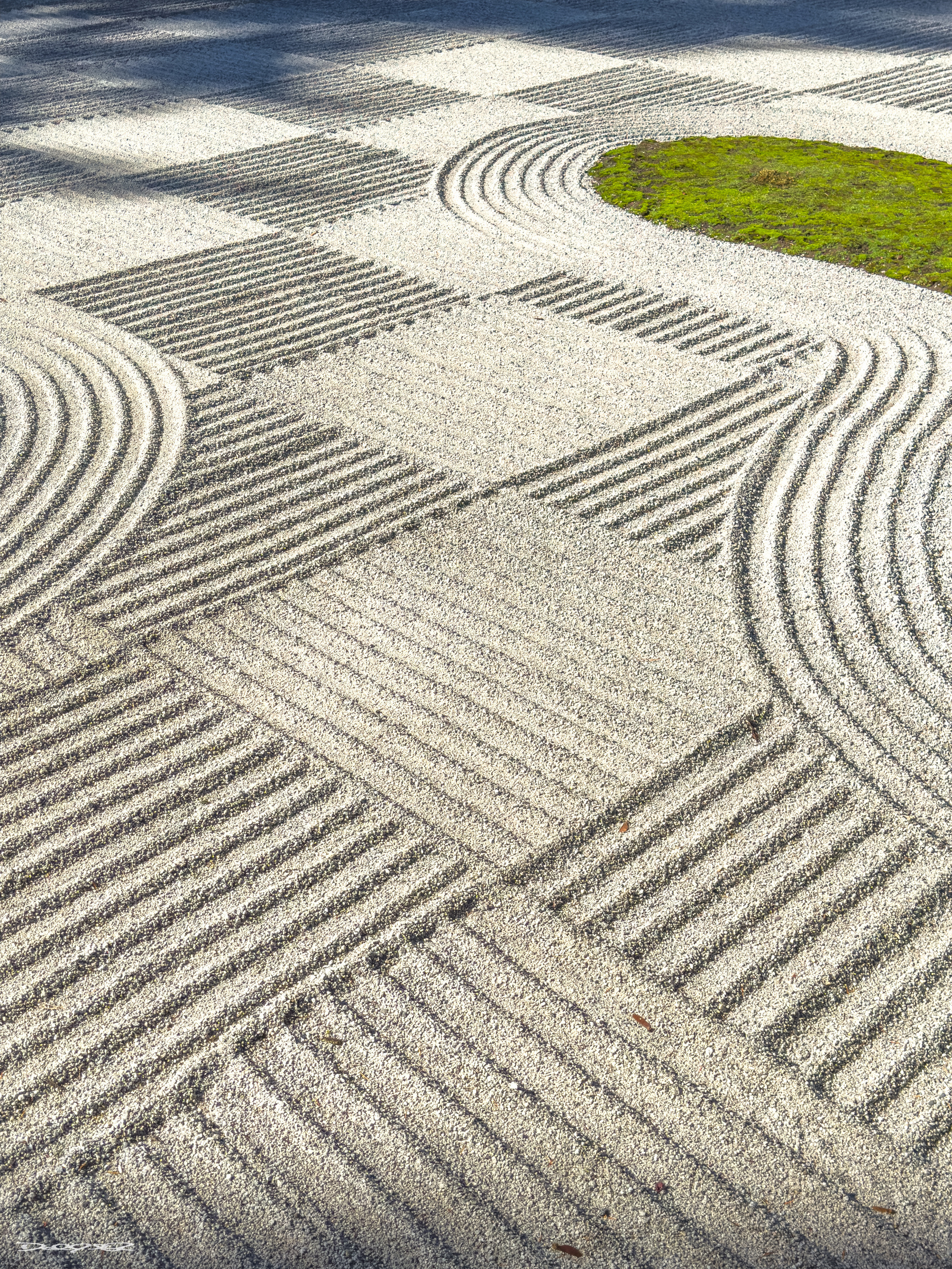 A  Ichimatsu Mori raked Japanese garden features intricate patterns in the gravel with a patch of green moss or grass. Ichimatsu - the checker board pattern is used once a year to celebrate the harvest moon.